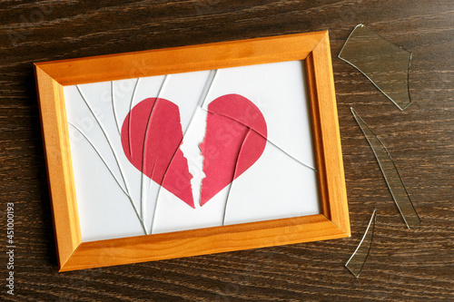 Two halves of a paper heart. Broken glass on a photo frame. Shards on the table