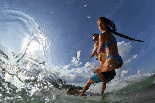 Lovely couple up on one kite board. Woman Riding On Kite surfer's Back and kiting on a sea © Oleg