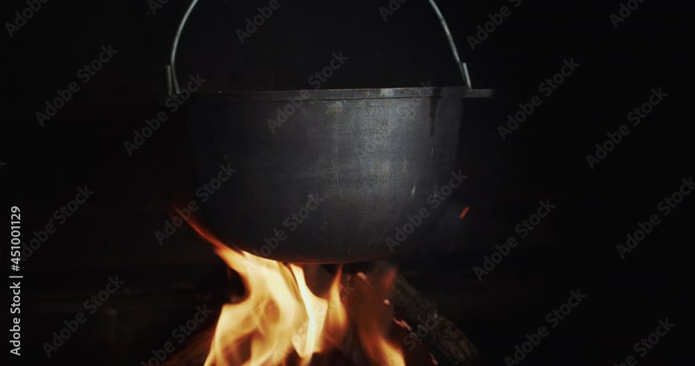 A cast-iron vat of boiling broth hangs in a wood-burning stove over an open fire. A cast-iron vat of boiling broth hangs in a wood-burning stove over an open fire.