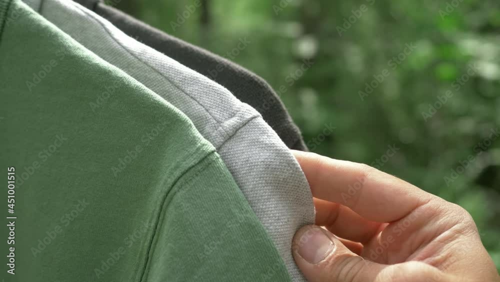 colorful organic cotton t shirts on hangers outdoor. sustainable fashion concept (eco fashion). textile and fashion industries, environmental problems, recycling, synthetic agricultural chemicals