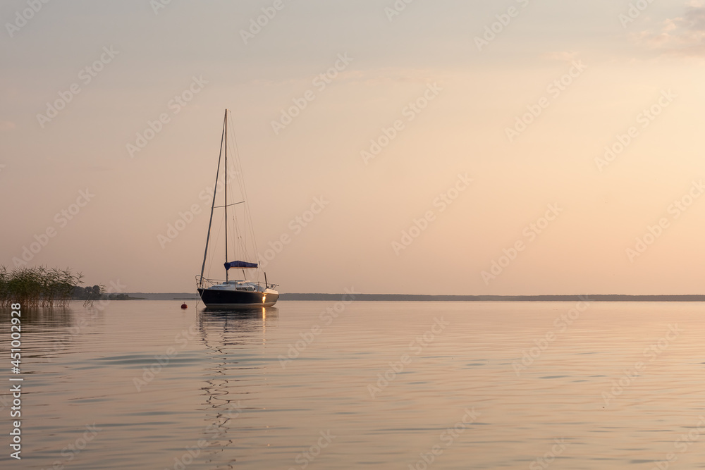 Sailing boat is illuminated by the sunset. Sunset on the lake.