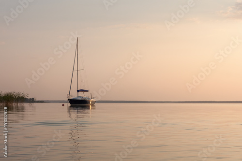 Sailing boat is illuminated by the sunset. Sunset on the lake.