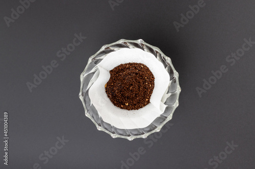 Prepared coffee grounds in the white filter paper and glass dripper. Ready to brew by hand pouring method.