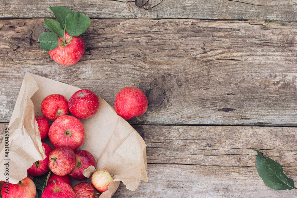 Red apples lie on a rustic wooden background in a torn paper bag. Eco-friendly packaging. Farmer's harvest, harvest Red apples lie on a rustic wooden background in a torn paper bag. Eco-friendly packaging. Farmer's harvest, harvest