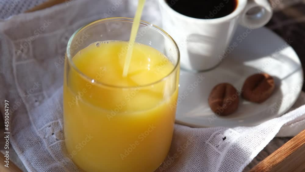Orange juice pouring into glass. Orange juice and coffee for breakfast Orange juice pouring into glass. Orange juice and coffee for breakfast