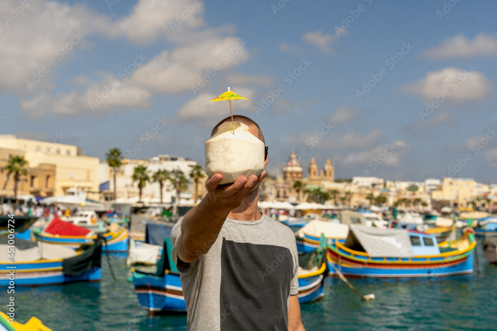 Young man holding I love Malta coconut drink in marsaxlokk, Malta