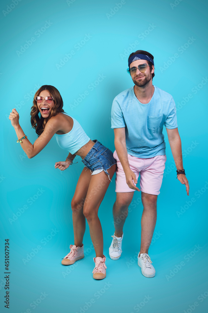 Fototapeta premium Full length of beautiful young couple having fun while standing against blue background