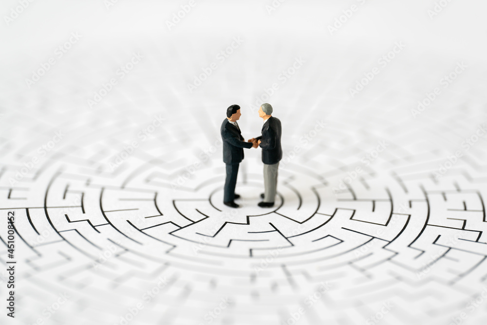 Miniature business people man shake hand partner client customers on center of maze with success dealing business using as contract commitment agreement investment and partnership business development Miniature business people man shake hand partner client customers on center of maze with success dealing business using as contract commitment agreement investment and partnership business development
