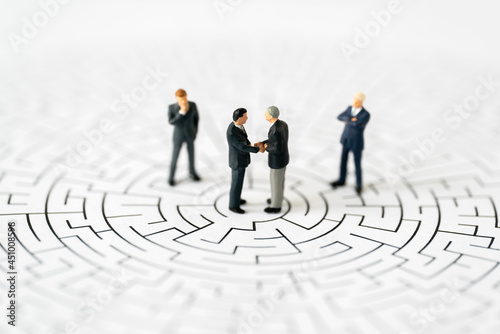 Miniature business people man shake hand partner client customers on center of maze with success dealing business using as contract commitment agreement investment and partnership business development