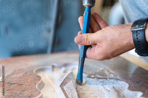 Caucasian man hands bushhammered a tombstone in a workshop,