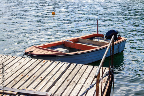 Small wooden boat moored next to wooden pier © olyasolodenko
