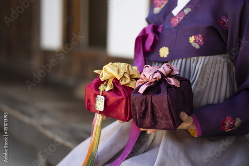 Woman in Korean traditional clothes holding traditional packages