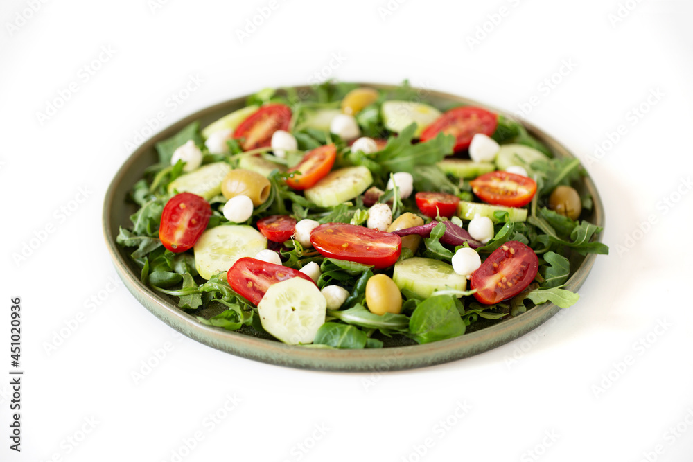 Arugula, tomato, cucumber, mozzarella and olive salad in a green plate. Shot with shallow depth of field. Arugula, tomato, cucumber, mozzarella and olive salad in a green plate. Shot with shallow depth of field.