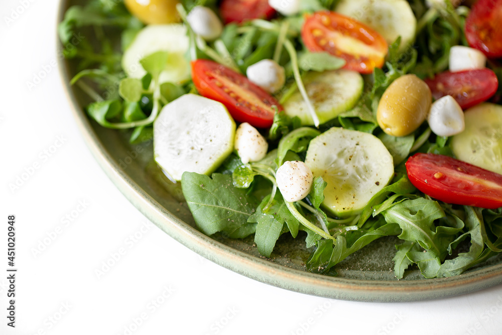 Arugula, tomato, cucumber, mozzarella and olive salad in a green plate. Arugula, tomato, cucumber, mozzarella and olive salad in a green plate.