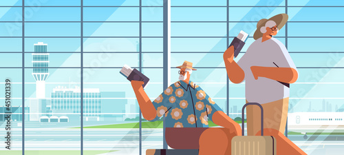 elderly couple of tourists grandparents with luggage holding passports and tickets ready to boarding at airport