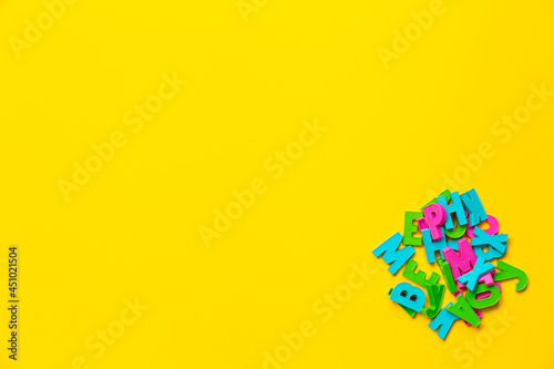 The English letters in the heap. Copy space. Colorful plastic alphabet isolated on yellow background. Preschool distance education banner. Online language course. Funny studying game. Primary school