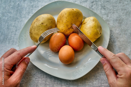 Obraz na plátne Three potatoes and three eggs, raw, uncooked and ready to be eaten