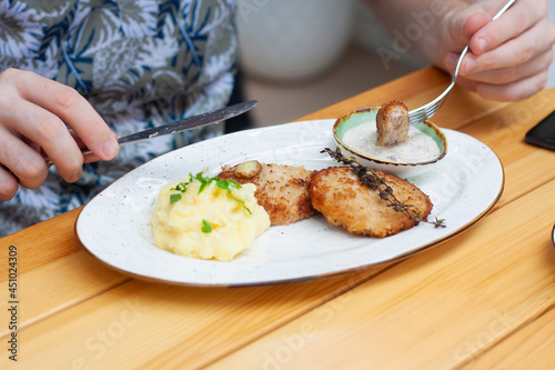 A man eats meat cutlets with mashed potatoes in a restaurant