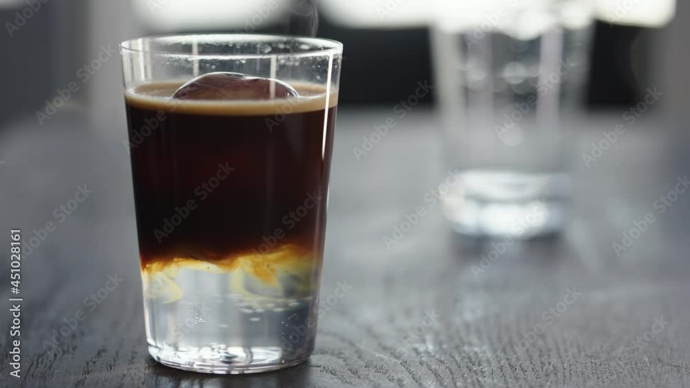 Slow motion making espresso tonic in tumbler glass, pour espresso in tonic with ice ball Slow motion making espresso tonic in tumbler glass, pour espresso in tonic with ice ball