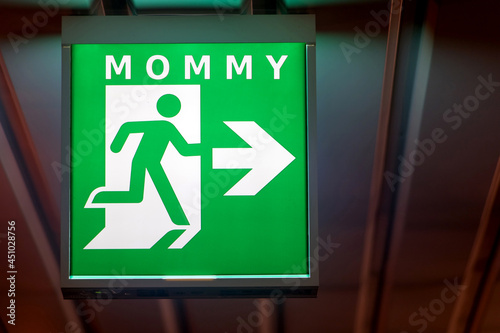 The emergency exit sign indicates the direction of way to mom.