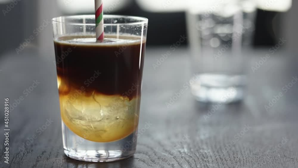 Slow motion making espresso tonic in tumbler with ice ball Slow motion making espresso tonic in tumbler with ice ball