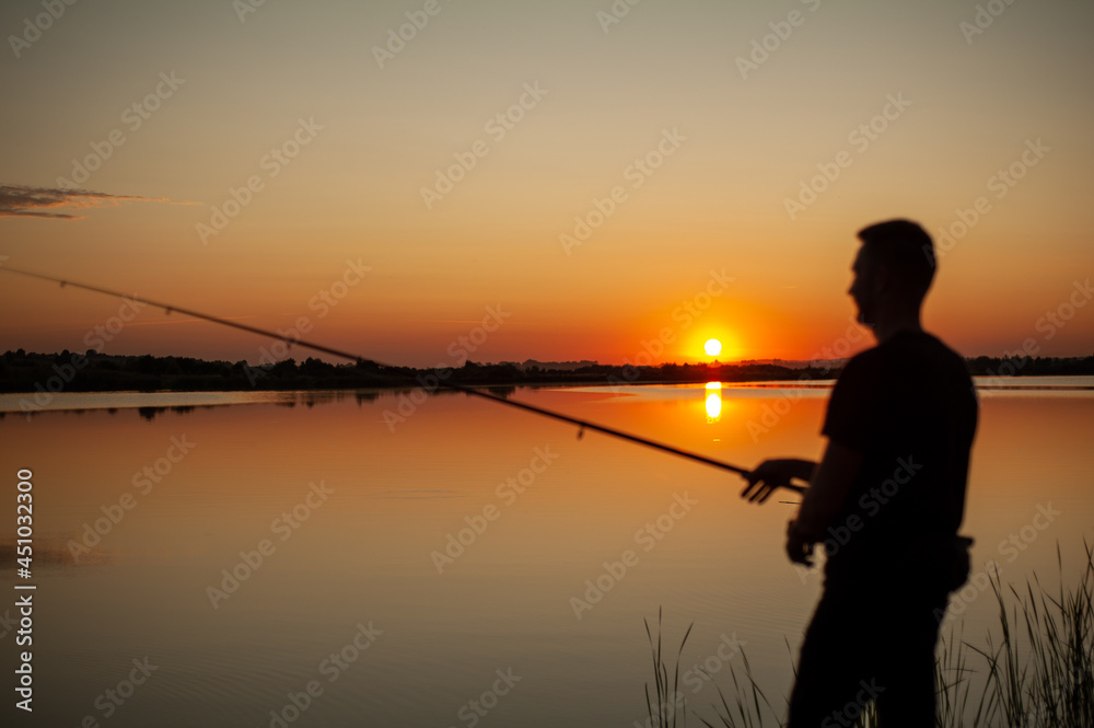 A fisherman silhouette fishing at sunset. Freshwater fishing, catch of fish