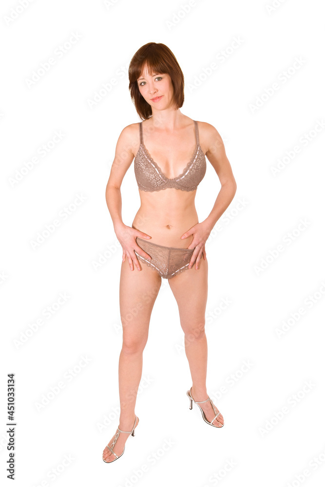 Full length portrait of an attractive brunette woman wearing beautiful lingerie, isolated in front of white studio background