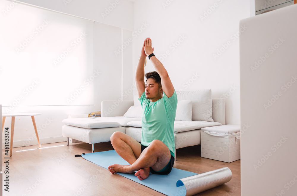 Young handsome Chinese man practicing yoga in the living room