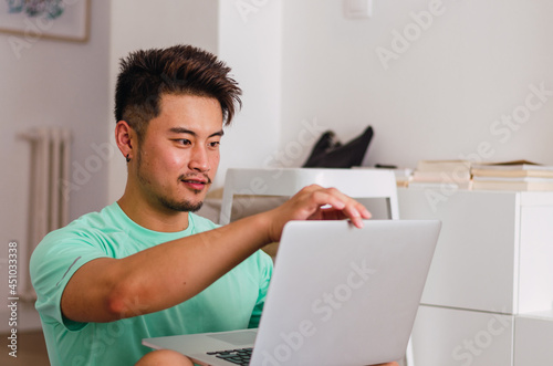 Portrait of young handsome Chinese man practicing yoga in the living room