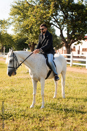 The young man is riding a horse on a farm