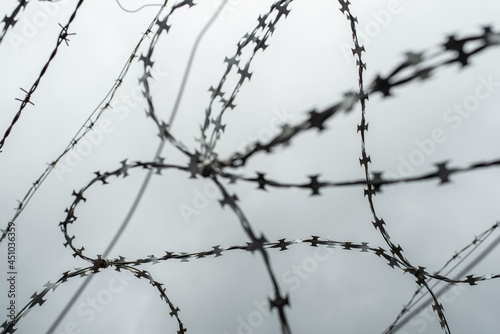 Out of focus photo of barbed wire against a grey cloudy sky. The heart shape in barbed wire.