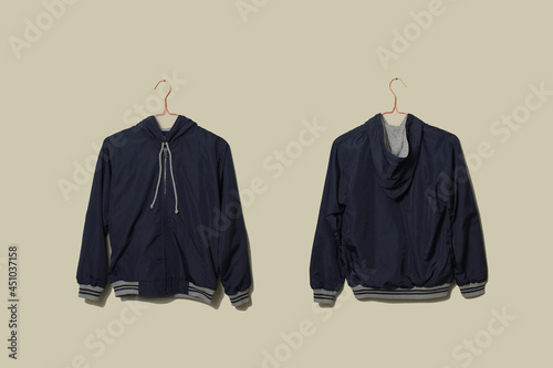 Blank blue sport jacket mockup set hanging on hanger, front and back side view on wall background photo