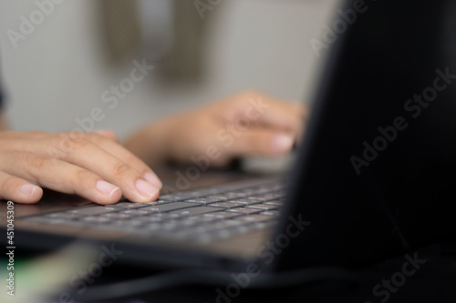 Woman's hand typing data and recording on her laptop.