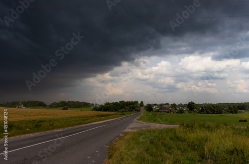 A large dark thundercloud over the road and the village 