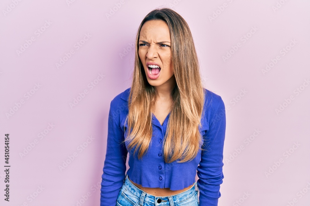 Beautiful hispanic woman wearing casual blue shirt angry and mad screaming frustrated and furious, shouting with anger. rage and aggressive concept.