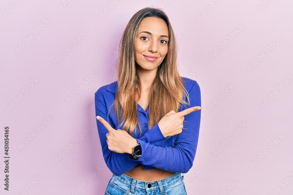 Fototapeta premium Beautiful hispanic woman wearing casual blue shirt pointing to both sides with fingers, different direction disagree