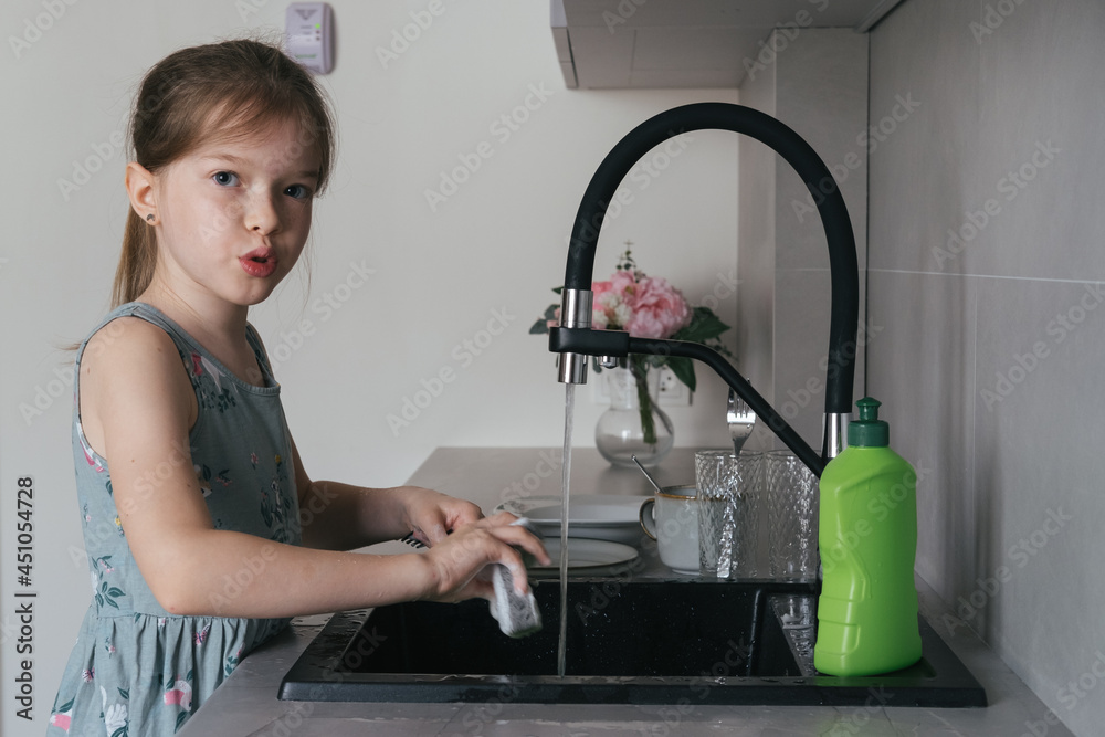 little girl helping mom wash the dishes