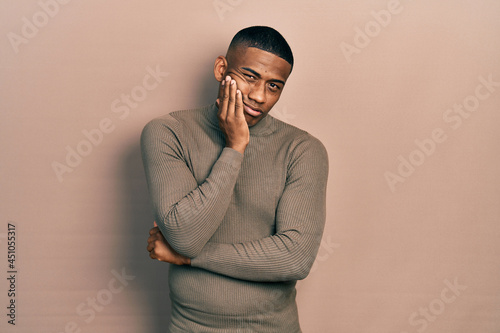 Young black man wearing casual turtleneck sweater thinking looking tired and bored with depression problems with crossed arms.