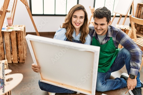 Two students smiling happy painting sitting on the floor at art school.