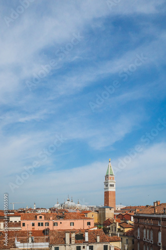 San Marco bell tower over traditional Venetian houses under blue sky in Venice, Italy