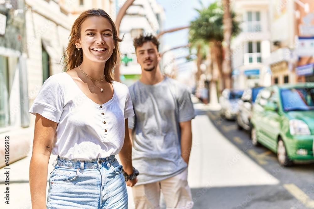 Young hispanic couple smiling happy holding hands standing at the city.