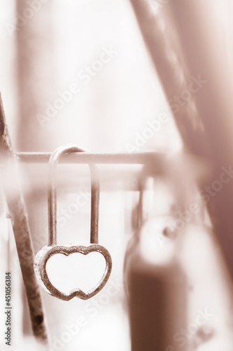 barn decorative padlock in the form of heart hangs on the railing of the bridge, symbol of the bride and groom connecting themselves by marriage, toned