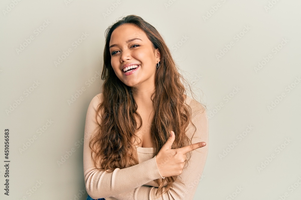 Young hispanic girl wearing casual clothes smiling cheerful pointing with hand and finger up to the side Young hispanic girl wearing casual clothes smiling cheerful pointing with hand and finger up to the side