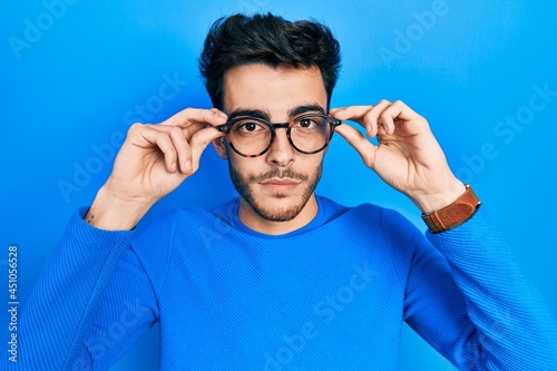 Young hispanic man wearing glasses relaxed with serious expression on face. simple and natural looking at the camera.