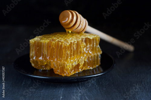 Honeycomb on a saucer. A honey spoon lies on the honeycomb.