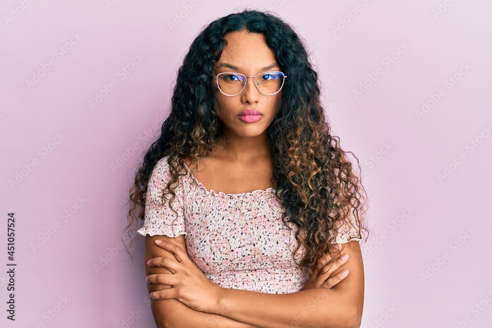 Young latin woman wearing casual clothes and glasses skeptic and nervous, disapproving expression on face with crossed arms. negative person. Young latin woman wearing casual clothes and glasses skeptic and nervous, disapproving expression on face with crossed arms. negative person.