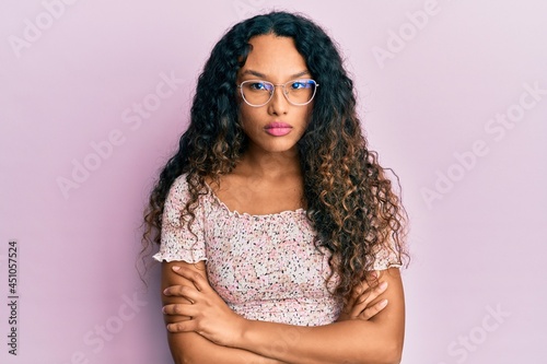 Young latin woman wearing casual clothes and glasses skeptic and nervous, disapproving expression on face with crossed arms. negative person.