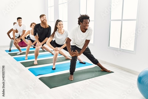 Group of young people smiling happy training legs exercise at sport center.