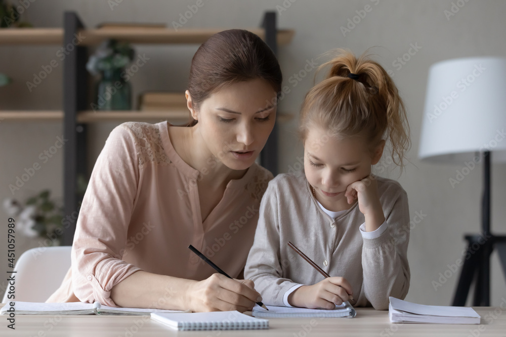 Loving young Caucasian mom help little daughter with homework assignment study write in notebook. Caring mother and small girl child handwrite take notes prepare home task. Education concept. Loving young Caucasian mom help little daughter with homework assignment study write in notebook. Caring mother and small girl child handwrite take notes prepare home task. Education concept.