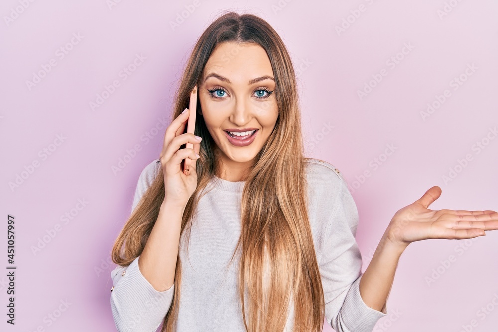Young blonde girl having conversation talking on the smartphone celebrating achievement with happy smile and winner expression with raised hand Young blonde girl having conversation talking on the smartphone celebrating achievement with happy smile and winner expression with raised hand